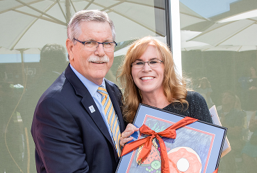 Chuck Day and Trulette Clays smiling and holdin a framed kids artwork