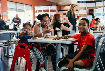 Mom and two children smiling during a meal service