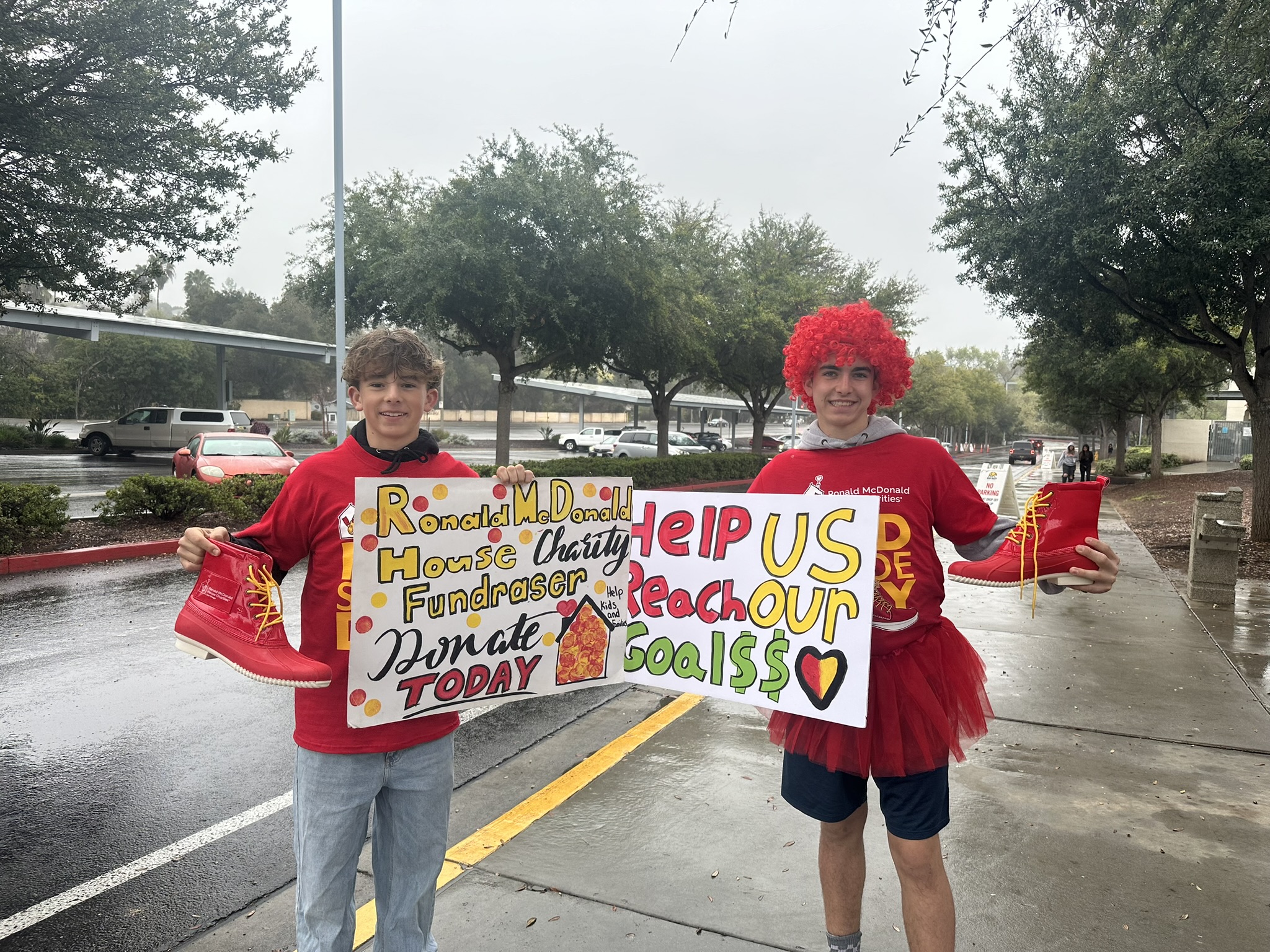 two boys dressed up for Red Shoe Day and holding home-made signs