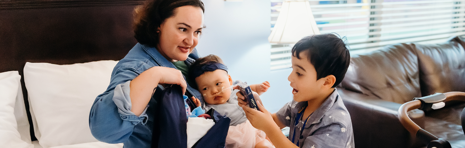 Mom holding baby and boy picking items out of a bag