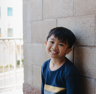 boy leaning against building smiling