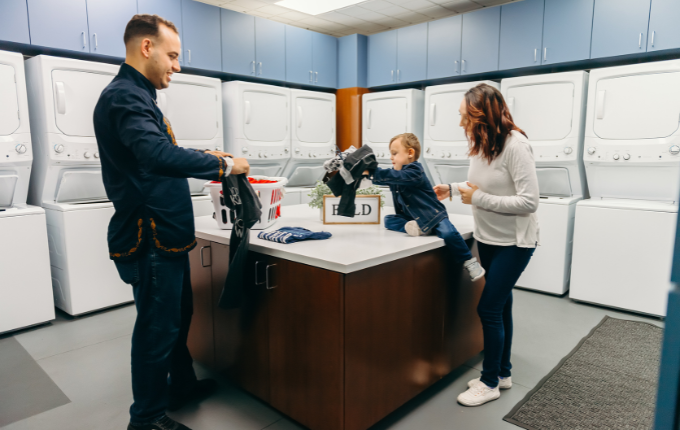 Parents and son folding clothes in a laundry room