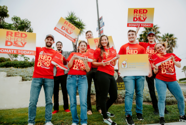 Red Shoe Day volunteers in red shirts holding Red Shoe Day signs