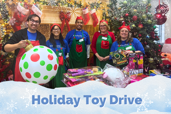 Holiday Toy Drive with volunteers standing in front of a fireplace with stockings