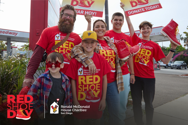 Red Shoe Day family in red shirts holding signs and boots