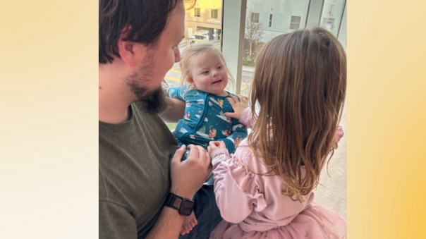 dad holding toddler son and daughter