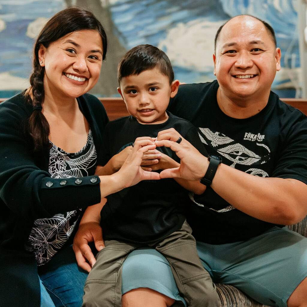 Mom, Dad, and child shown in a heart hands pose at San Diego's Ronald McDonald House.
